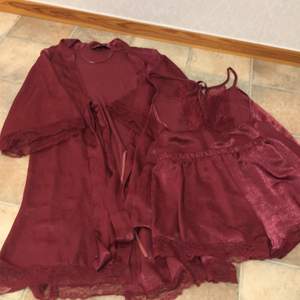 Pyjamas sett i silkes i färgen vinrött. Använd 1 gång. Tillkommer morgonrock , linne och shorts med lite spets på sidorna av plaggen. 