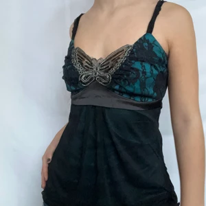 Fjäril linne  - Svart och blått linne med fjäril och spetsdetaljer på bysten. Kan knytas och där med spännas i ryggen. Visas på en S men passar även xs då den går att spänna. Köpare står för 24kr frakt. Plagget är i gott defetfritt second hand skick. Högsta bud 240kr. Avslutas 24h och markeras med att plagget markeras sålt så tills dess, bud app privat!! KÖP DIREKT FÖR 250!