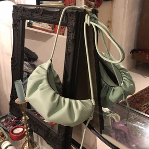 Mintgrön väska - Superfin mellanstor väska. Den är mintgrön med detaljer vid mitten. Går att justera till exakt längd, både axelväska och som korsar. Guldig dragkedja perfekt för att få in lite färg i vardagen. Nypris 268kr