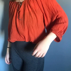 Orange blus, Large.  - (För stor för mig som syns). Skön, höstig tunn och puffig blus med liten brun, läderaktig snöranordning som detalj vid halsen. Går att knyta om. 
