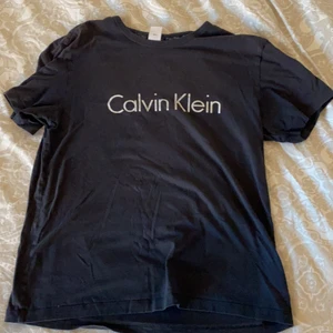 Calvin Klein tröja  - En svart Calvin Klein tröja som är synliga tecken på användning . En fläck uppe vid kragen och lite sliten text så därav priset. 