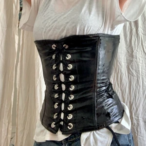 Korsett - Fin korsett i lack. Den har några ställen där det har flagnat lite men tycker personligen att det bra ger en mer ruff look. Den är lätt att snöra och kan snöras upp mycket mer än på bilden. Alltså passar den de flesta storlekarna. Jag är storlek s om ni vill ha nåt att jämföra med:). Säljer till högsta budande.