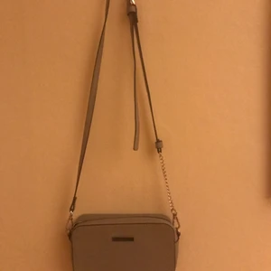 Axelväska - Grå axelväska i skinnimitation med justerbart axelband. Andvänd fåtal gånger. Finns ficka inuti. Man kan ta av axelbandet om det skulle önskas.