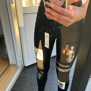 Svarta jeans med motiv - Jag säljer ett par skit snygga jeans jag aldrig använt och fick hem i förigår. Prislapp kvar. Jag säljer för det är för tajta för tajta för mig. Köpta från Storbritannien, säljer för jag inte kunde lämna tillbacka. Fick betala både tull och moms på 1980kr för tre jeans som inte passar som jag just nu säljer. ÄLSKAR DEM, men ingen passar:/ vet att det är dyrt men de kostade så, byxorna is one of a kind, då inte många säkert beställt från Sverige pga tullen.  OBSEVERA! Tvättas bara i 30 grader!! 