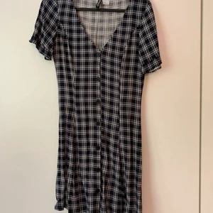 Rutig klänning med knappar - Mörkblå/vit rutig klänning med knappar samt små volanger vid ärmslut🌼 Frakt tillkommer😊