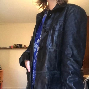 Svart skinnkappa - Svart skinnkappa som varit min bebis!!! Den är väl använd och har lite slitna knappar därav det billiga priset! Har dock alltid jackan öppen så knapparna spelar ingen roll!