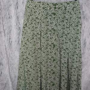 Underbar grön och vitblommig lång/midi kjol från Monki i storlek s. Kjolen har resor i midjan samt knappar och fickor.