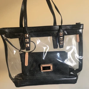 Guess väska - Skit cool Clear Guess väska fick i present några år sen fast har bara legat i mitt skåp så den ser helt ny utt. Säljer för har inte kommit till andvänding. Kommer med en litten väska för pengar och sånt.(köpare står för frakt) kan möttas up i Odenplan eller TC. Skriv för mer frågor :))