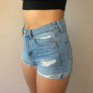 Ljusblåa jeansshorts med slitningar. Modellen är 160. 