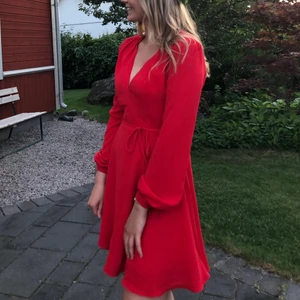 Klänning  - Säljer denna så himla fina klänning i en sån fin röd färg. Klänningen kommer från Nelly och är använd max 2 gånger. Klänningen har ett tunt band som man knyter i midjan, perfekt v-ringning och lite luftigare ärmar. Frakt på 66kr tillkommer🥰