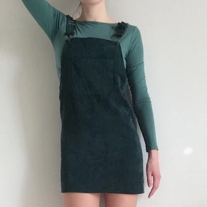 Manchesterklänning - Vintage hängsleklänning i mörkgrön manchester. Inköpt på Rokit Vintage i London. Lite kort på mig som är 176 cm, skulle nog passa en XS-S, beroende på hur man vill att de ska sitta.