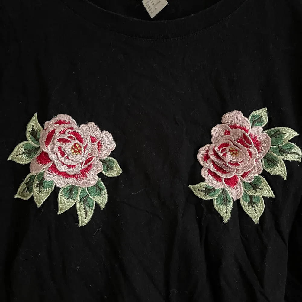 En svart T-shirt med två rosor på bröstet. Lite skrynklig dp den legat i en låda för länge så nu är det dax för en ny ägare! . T-shirts.