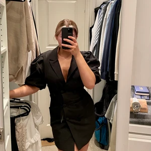 Svart kavaj klänning - En svart kavajklänning som aldrig är använd. Den är svart och knäpps med knappar. Klänningen sitter väldigt fint mot kroppen. 