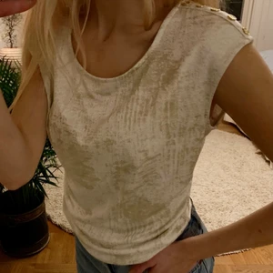 Guess t-Shirt  - T-shirt från GUESS i storlek XS. Den är beige/vit med guldig/glittriga inslag. Säljer för 100kr🌸