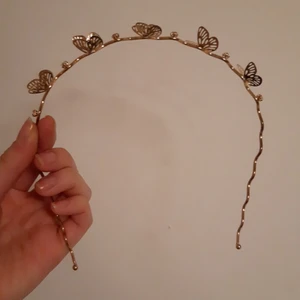 Guldigt diadem med fjärilar - Guldigt diadem i metall med fjärilar och små stenar. Något år gammalt men aldrig använt, säljer pga att jag nog inte kommer använda den. Som sagt inte helt ny så minns inte var den köptes.