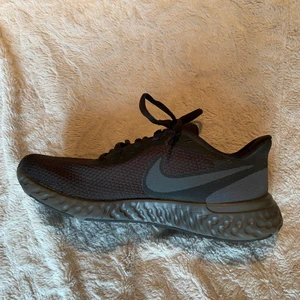 Träningsskor från Nike - Ett par svarta träningsskor från Nike. Använda en gång. Snygg modell med Nike-loggan som detalj på vardera sida av skorna. Skor som funkar både inomhus och utomhus. Org. pris: 500kr