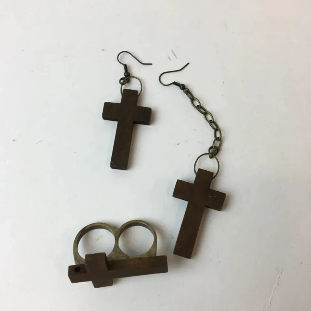 Kors örhängen och en dubbel ring med kors, gjort av trä. Ena örhänget är längre än det andra.. Accessoarer.