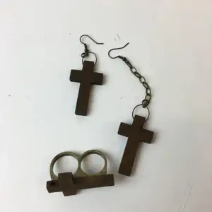 Kors örhängen och en dubbel ring med kors, gjort av trä. Ena örhänget är längre än det andra.