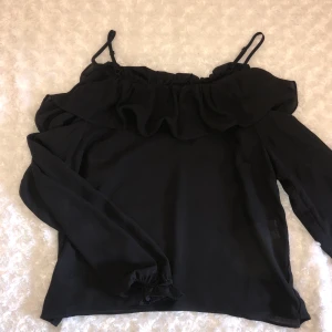 Svart off-shoulder topp - Svart off-shoulder topp med små band som håller uppe tröjan☺️ tröjan är ganska tunnt tyg och skulle säga att den passar både M och S, den har även fina volanger vid ärmarna och över axlarna (se bild 3)💞