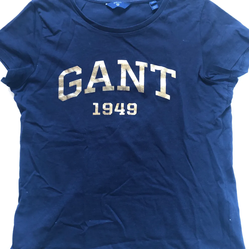 Fin marinblå t-shirt med guldtryck från Gant. I storlek XS. . T-shirts.