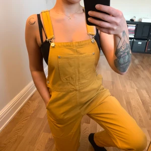 Gula hängselbyxor från Monki - Hängselbyxor i storlek S från Monki. Jag har sytt in byxbenen till en mer slimmad look, ordentligt med symaskin. I gott skick. Köparen står för frakt som tillkommer 💌