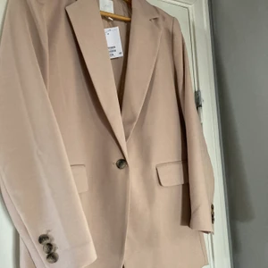 Vårfin, oanvänd kavaj från H&M - Säljer min fina beige kavaj från H&M som inte kommit till användning. Helt ny med tag kvar. Storlek 42. 