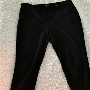 Svarta kostymbyxor från Next - Snygga kostymbyxor i str 42 från Next petite. En knapp sitter lite löst men annars i bra skick. Kan hämtas, mötas upp om i närheten eller levereras, men köparen står för frakt.