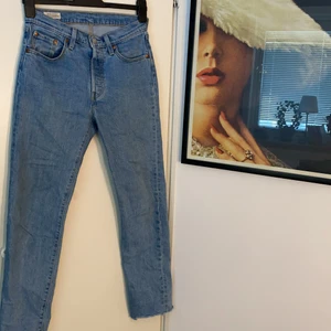 Levis Jeans - Snygga ljusblåa Levis 501 i storlekarna Midja-25 Längd-30 (dam). Har använts men är i riktigt bra skick. De är klippta på ändorna av benen och de köptes så från Levis butiken. Istället för dragkedja finns det knappar som inte syns (kontakta för mer bilder). Originelpriset på dessa är 1100kr! 