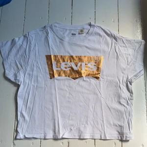 Snygg Levi’s t-shirt - Jättefin Levi’s t-shirt med guld tryck. Den är knappt använd så jättebra skick. Säljer pga av att den nt kommer till användning!! 💓 Den sitter lite oversize så skulle passa storlekar över och under S beroende på hur man vill att den ska sitta. 