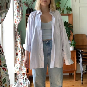 Vit-Lila randig skjorta - Skjorta köpt secondhand i vit-lila randig färg. Skicket är som nytt och den är stor i storlek, skulle gissa på XL så passar många olika beroende på hur man vill att den ska sitta. Väldigt fin och är lätt att klä upp men också att ha till ett par jeans som jag har. 