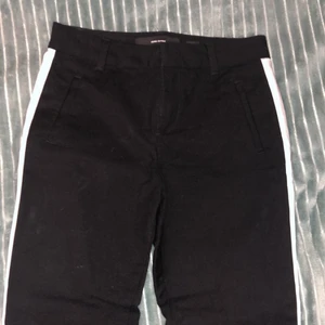 Svarta kostymbyxor stl XS/30 - Svarta kostymbyxor med vita ränder, saknar fickor. 