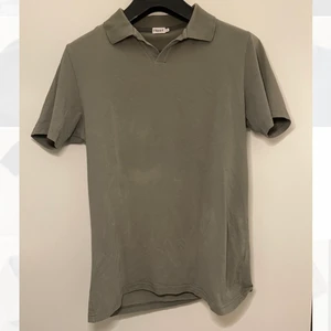 Grön/grå piké från Filippa K - Stilren piké från Filippa K i en cool ”smutsgrön” färg. Den är gjord av ett behagligt, lite stretchigt material och har en snygg knapplös krage med bra struktur. Modellen är fortfarande aktuell med nypris 800kr.