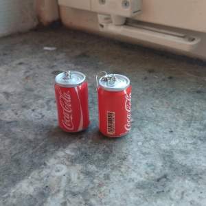 Detaljerade, lätta Coca-Cola örhängen.