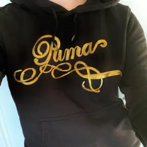 Svart hoodie från Puma med loggan broderad i guldiga paljetter ✨ Använd men har mycket kvar att ge! Storlek M men passar mig som normalt bär S     Kolla gärna in min andra annonser! 
