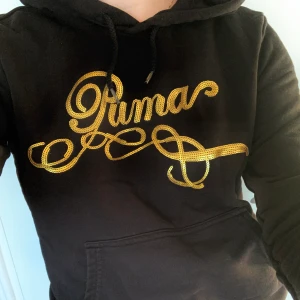 Hoodie  - Svart hoodie från Puma med loggan broderad i guldiga paljetter ✨ Använd men har mycket kvar att ge! Storlek M men passar mig som normalt bär S     Kolla gärna in min andra annonser! 