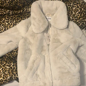 Mysig fuskpälsjacka NAKD - ny & oanvänd jacka i suuperskönt material från NAKD. Väldigt bra fuskpäls i färgen grå-vit. Med dragkedja samt två små fickor. Verkligen super skön att ha på sig & hyfsat varm. Skickar bilder på hur den sitter på vid önskemål. Köpt för 799kr. Storlek 36