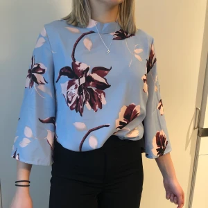 Mönstrad blus  - En blå blus med rosa/lila blommor på, även en lite öppen rygg. Säljer då det inte är min stil längre. Köparen står för frakten.