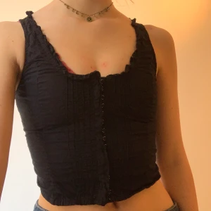 Svart linne - Sjukt snyggt linne!! Har en ”korsettliknande” gargong då den knäpps där fram med spännen. Väldigt tajt och croppad modell. Skitsnyggt!
