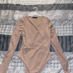 Super Fin Body i ribbat material. - Superfin och snygg body från boohoo i ribbat material. Skulle säga att den e beige rosa. Knappt använd därav så sälja den. Den har inga frakturer och är i gott skick. 
