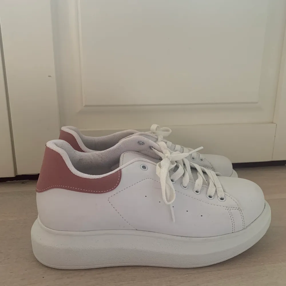 Vita sneakers med rosa detalj från Nelly, aldrig använda i st 38. Skor.