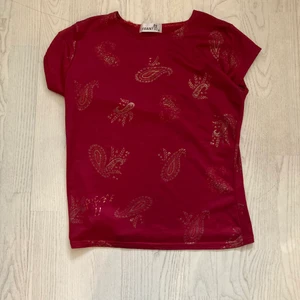 Mörk röd t shirt  - Fin mörkröd t shirt med guldtecken.