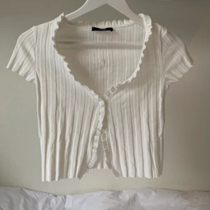 Vit ribbad topp! - Vit ribbad topp från Bershka med knäppning framtill (går alltså att ha öppen som kofta om man skulle vilja det). Endast använd en gång så i nyskick! Är relativt lite i storlek mer som en xs-s. 