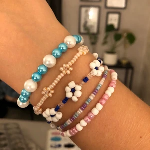 Pärlade armband - Säljer armband som jag har pärlat själv🤍🤍 Kolla mina andra annonser för fler pärlade smycken. Pris för ett med bara små pärlor: 25kr, pris för ett med stora pärlor: 30kr, pris för ett med blommor: 40kr🥰 Kom gärna med egna förslag på färg å design, frakt tillkommer på 13kr:)