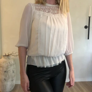 Beige topp med fina detaljer  - Topp med fina detaljer och flera lager tyg, silkes tyg under vilket gör den väldigt skönt. Halvhög hals. 