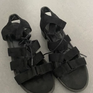 Svarta skor i ”mocka” - Svarta sandaler / sandaletter med låg klack och snörning. Användbar några gånger. Från New Look. Ganska stora i storleken, jag brukar ha mellan 39-40 i skor och dessa passar mig.