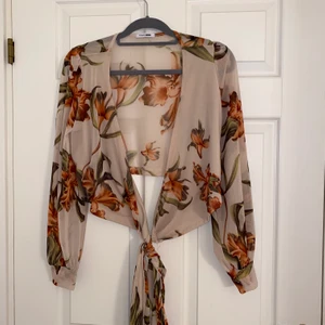 Blommig Crop tie top - En genomsynlig beige tröja som man kan knyta.