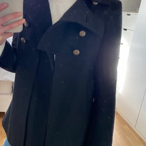 Jacka/kappa -  Jätte snygg svarta kappa med fina detaljer. Säljs då den inte kommer till användning. Aldrig använd. Storlek 8/34. Frakt tillkommer.  