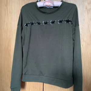 Korsett tröja - Militär grön tröja med band som håller i hop topen och botten, man kan se imellan stygnerna så kom-ihåg att bära något under. Lite noppig men anars inga andra fel