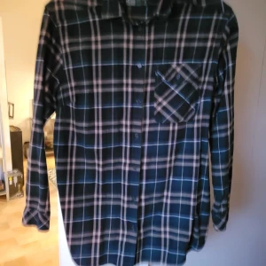 Skjorta - Rutig skjorta som är lite längre än normal. Knappt använd. Från djur och rökfritt hem. Kan skickas mot fraktkostnad 