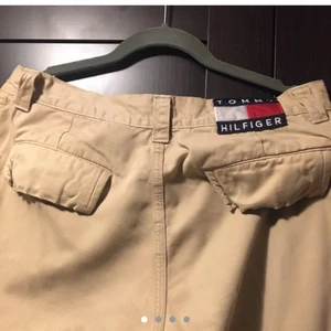 Beige tommy hilfiger bukse - Vintage tommy hilfiger bukse fra Depop. Logoen både bak på buksa og framme